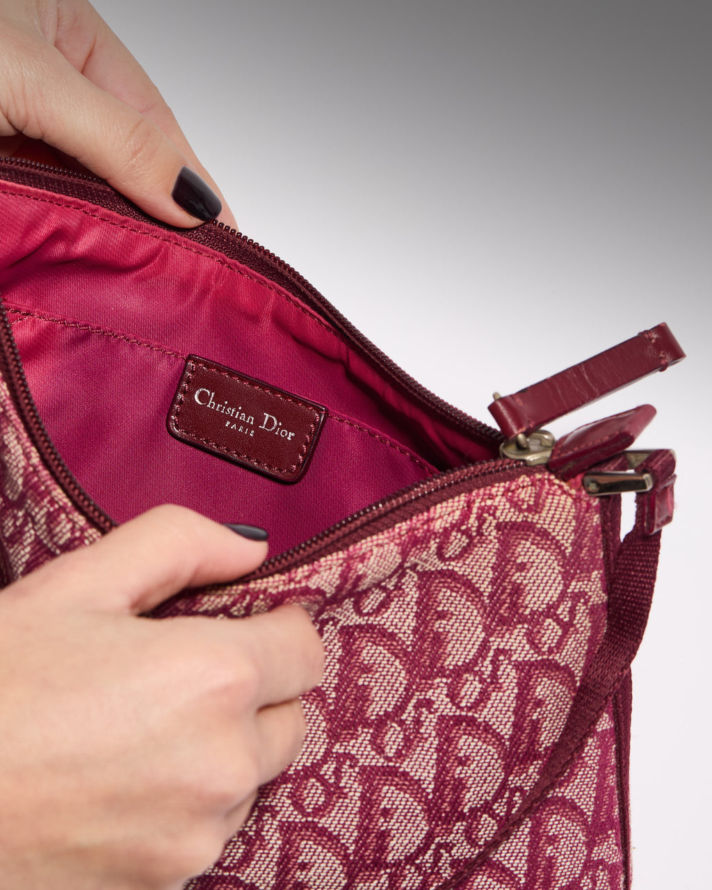 Interior of vintage Dior Trotter canvas shoulder bag with burgundy lining and logo label
