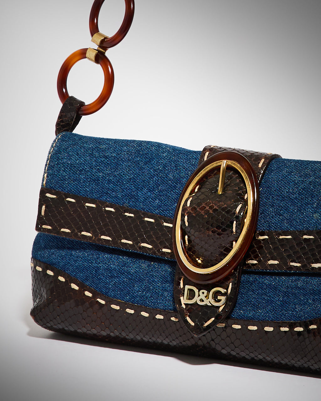 Detail of vintage Dolce & Gabbana patchwork denim handbag with logo clasp and tortoiseshell handle
