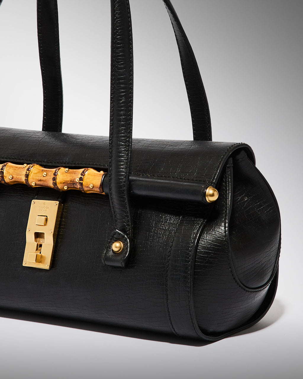 Side detail of vintage Gucci bamboo bullet bag in black leather with bamboo accent